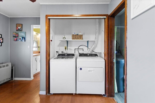 laundry room with radiator heating unit, light hardwood / wood-style floors, wood walls, and independent washer and dryer