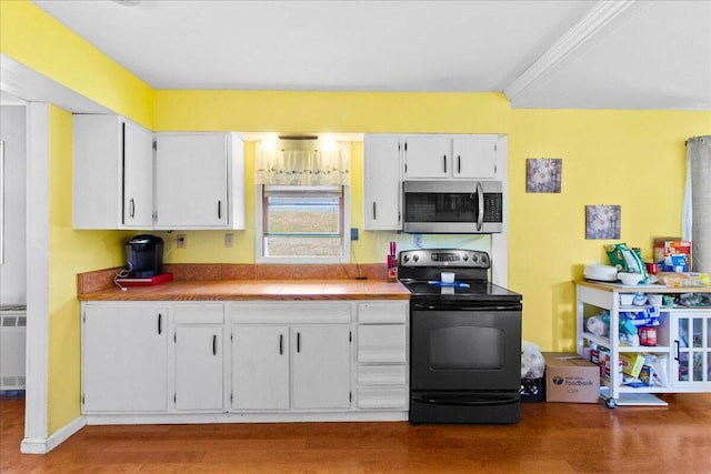 kitchen featuring radiator, white cabinetry, black range with electric cooktop, wood-type flooring, and ornamental molding