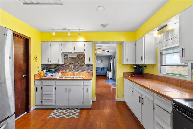 kitchen featuring sink, ceiling fan, dark hardwood / wood-style flooring, white cabinetry, and stainless steel refrigerator