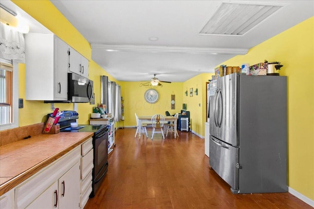 kitchen with appliances with stainless steel finishes, dark hardwood / wood-style floors, white cabinetry, and ceiling fan