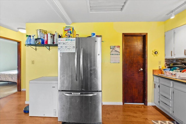 kitchen with stainless steel refrigerator, rail lighting, tasteful backsplash, refrigerator, and light hardwood / wood-style floors