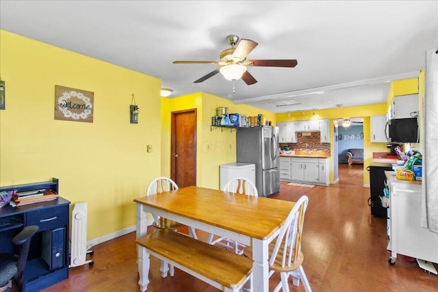 dining room featuring ceiling fan, sink, and dark wood-type flooring