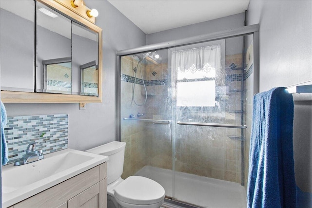 bathroom with vanity, backsplash, toilet, and a shower with door