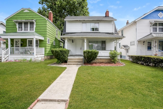 view of front of home featuring covered porch, a chimney, a front yard, and roof with shingles