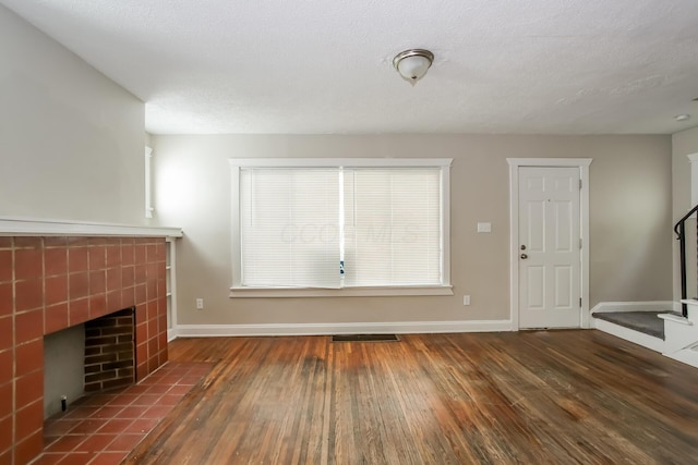 unfurnished living room featuring stairway, baseboards, hardwood / wood-style flooring, and a tile fireplace