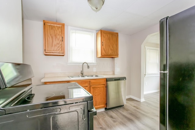 kitchen with light countertops, stainless steel dishwasher, freestanding refrigerator, electric stove, and a sink