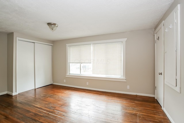 unfurnished bedroom with baseboards, wood-type flooring, and a textured ceiling