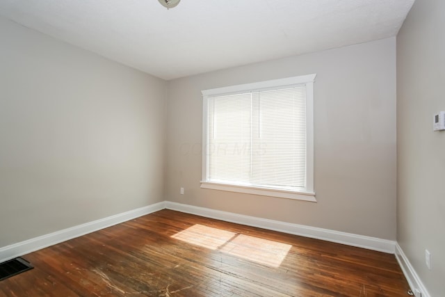 unfurnished room featuring dark wood-type flooring, baseboards, and visible vents