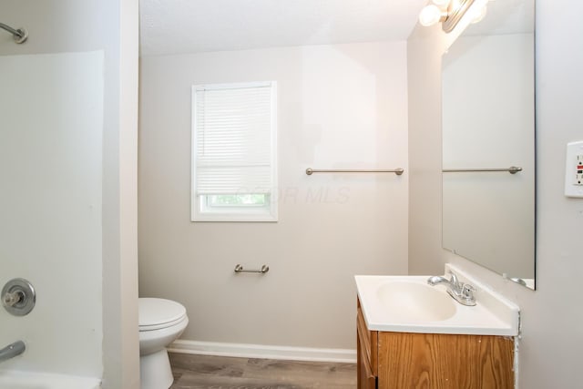 bathroom featuring toilet, shower / tub combination, wood finished floors, baseboards, and vanity