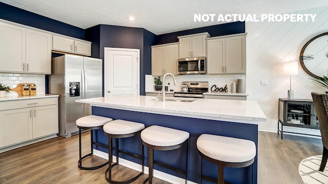 kitchen featuring backsplash, an island with sink, light hardwood / wood-style floors, and appliances with stainless steel finishes