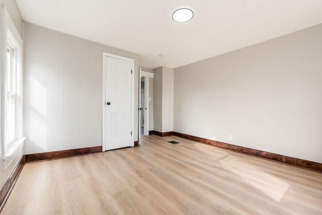 spare room with wood walls and light wood-type flooring