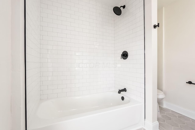 bathroom with tile patterned flooring, tiled shower / bath combo, and toilet