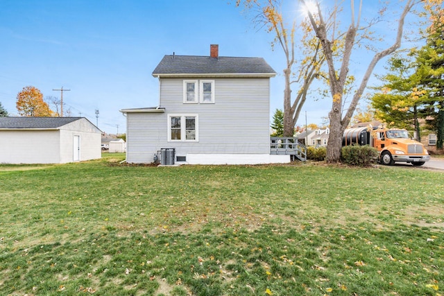 rear view of property featuring a lawn and central AC unit