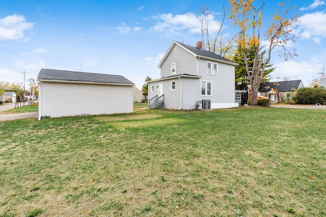 rear view of house featuring a lawn and central AC unit