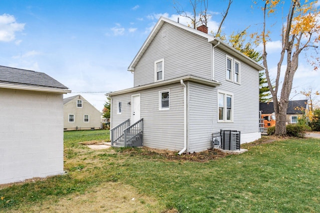 back of property featuring central AC unit and a yard