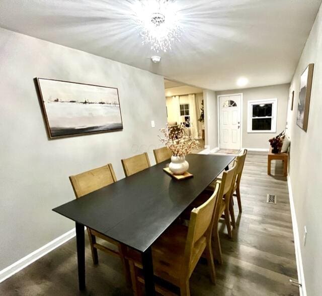 dining space featuring dark hardwood / wood-style flooring and a notable chandelier