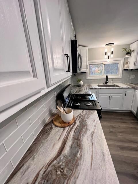 kitchen with white cabinets, tasteful backsplash, black electric range, and sink