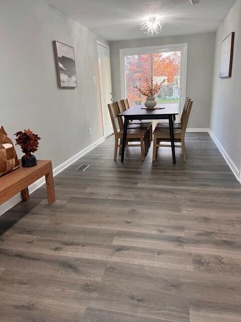 dining area with dark wood-type flooring and an inviting chandelier