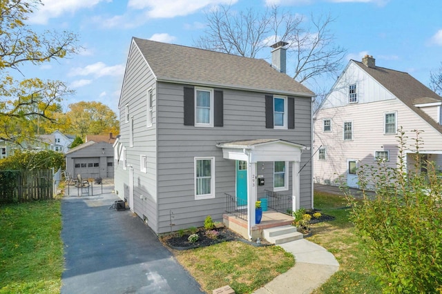 view of front facade featuring a garage, an outbuilding, and a front lawn