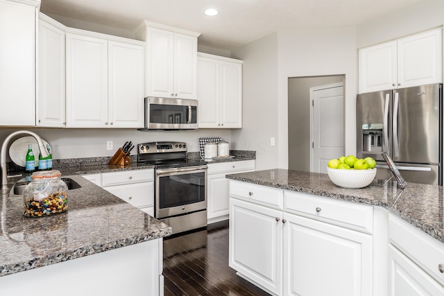 kitchen with dark stone counters, white cabinets, sink, dark hardwood / wood-style floors, and appliances with stainless steel finishes