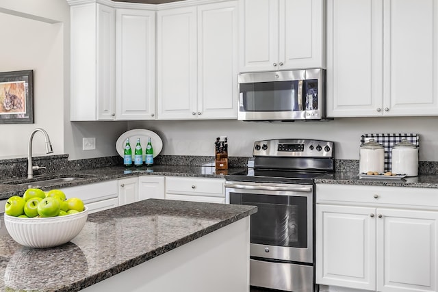 kitchen featuring dark stone countertops, white cabinetry, sink, and appliances with stainless steel finishes