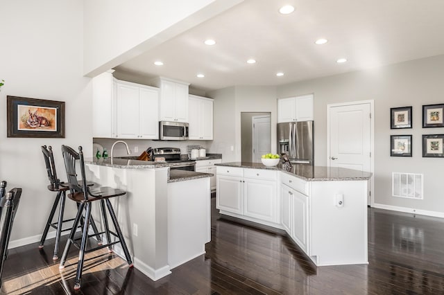 kitchen featuring white cabinets, a center island with sink, and stainless steel appliances