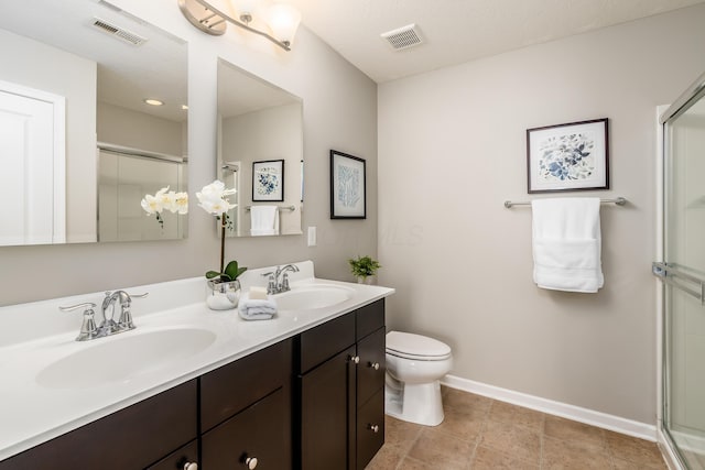 bathroom featuring tile patterned flooring, vanity, toilet, and a shower with door