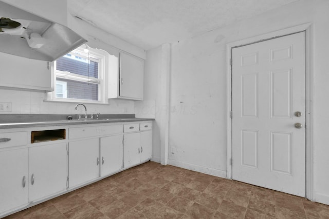 kitchen featuring a textured ceiling, white cabinetry, and sink