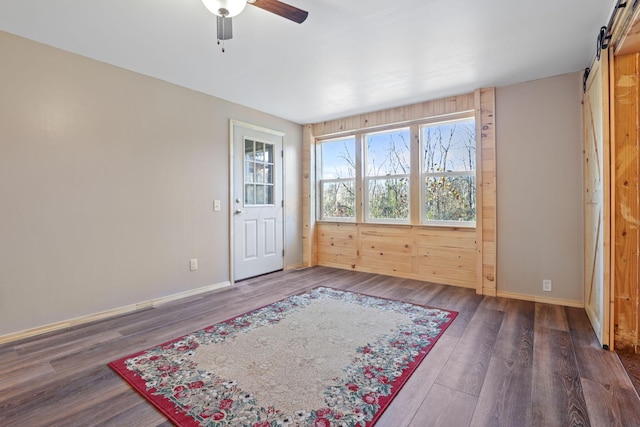 interior space featuring a barn door, ceiling fan, and dark hardwood / wood-style floors