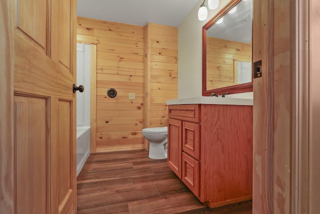 bathroom with a bathtub, vanity, wood walls, toilet, and wood-type flooring