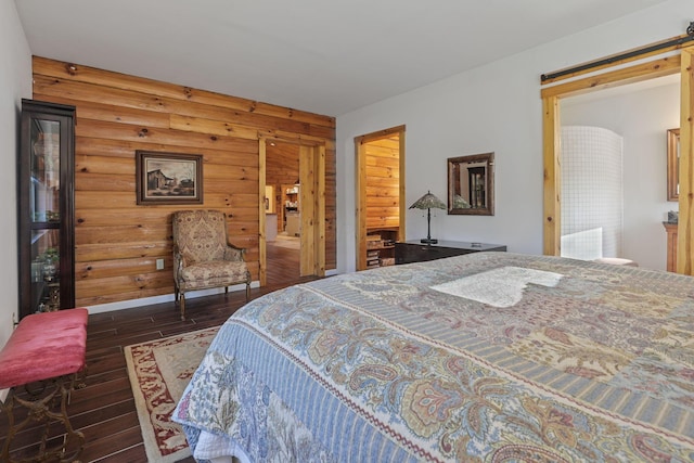 bedroom with dark hardwood / wood-style floors, wood walls, and log walls