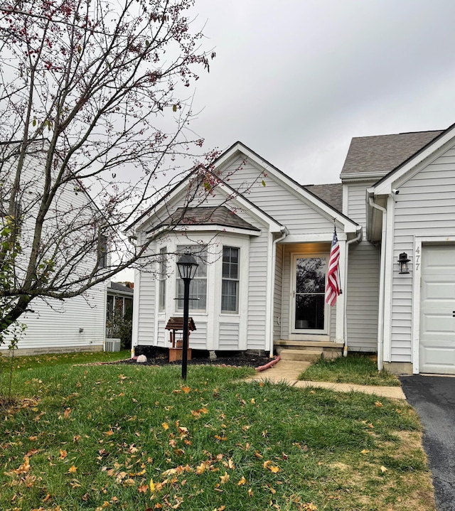 view of front of property featuring central air condition unit, a front yard, and a garage