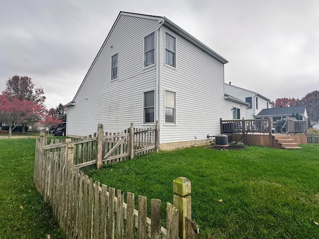 view of side of property featuring a deck, central AC unit, and a lawn