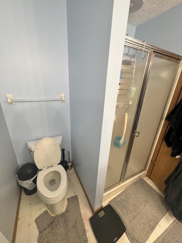 bathroom featuring a shower with shower door, a textured ceiling, and toilet