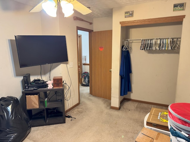 bedroom featuring ceiling fan, a closet, light carpet, and a textured ceiling