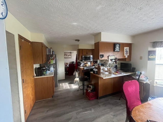 kitchen featuring a textured ceiling, dark hardwood / wood-style floors, and kitchen peninsula