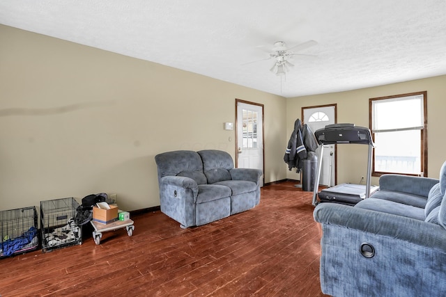 living room featuring ceiling fan, dark hardwood / wood-style flooring, and a textured ceiling