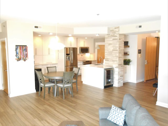 dining area with sink, wine cooler, and light hardwood / wood-style flooring