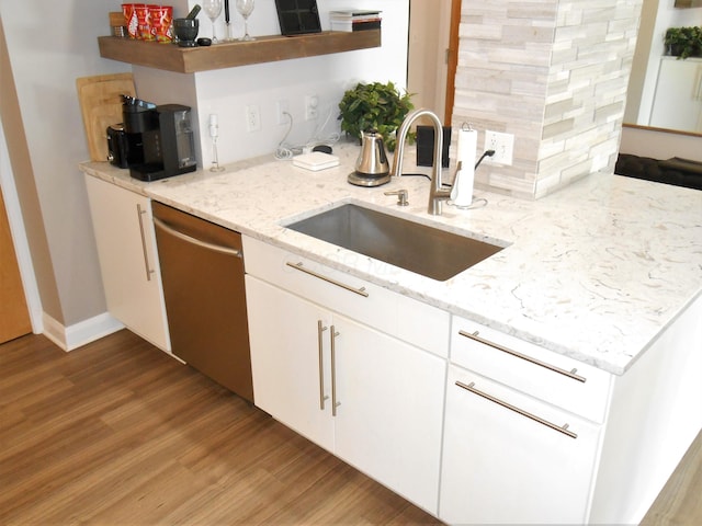 kitchen featuring dishwasher, white cabinets, sink, light stone countertops, and light hardwood / wood-style floors