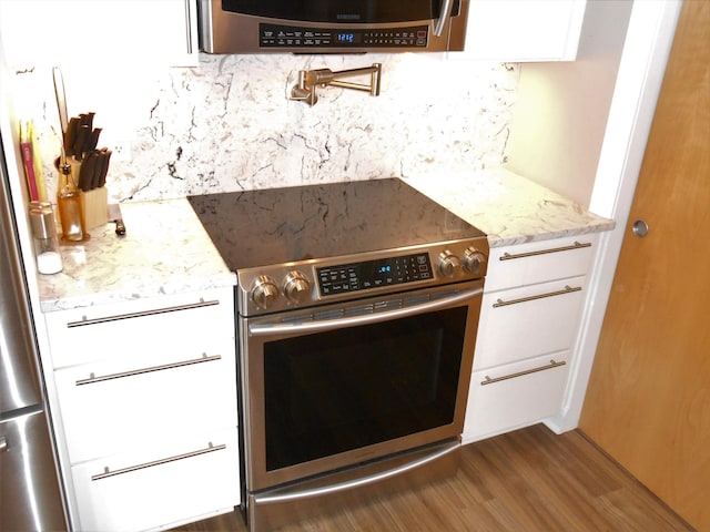 kitchen featuring white cabinetry, light stone countertops, dark hardwood / wood-style floors, decorative backsplash, and appliances with stainless steel finishes