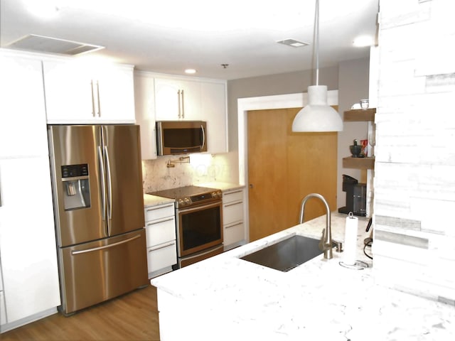 kitchen featuring sink, stainless steel appliances, light stone counters, white cabinets, and light wood-type flooring