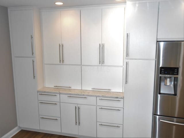 kitchen with white cabinets, stainless steel fridge, dark hardwood / wood-style flooring, and light stone countertops