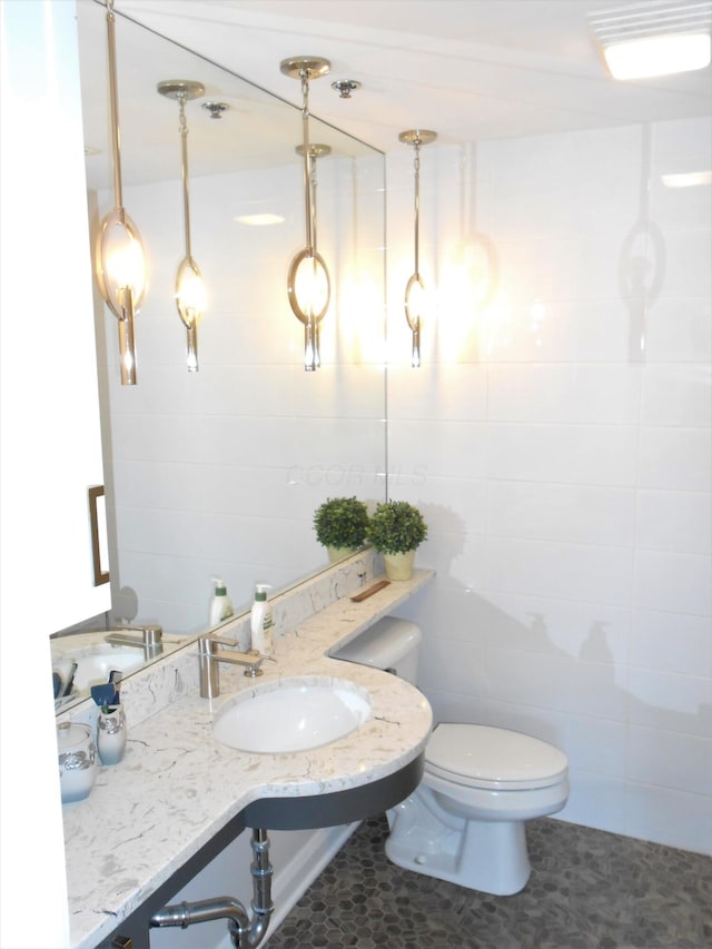 bathroom with tile patterned floors, toilet, sink, and tile walls