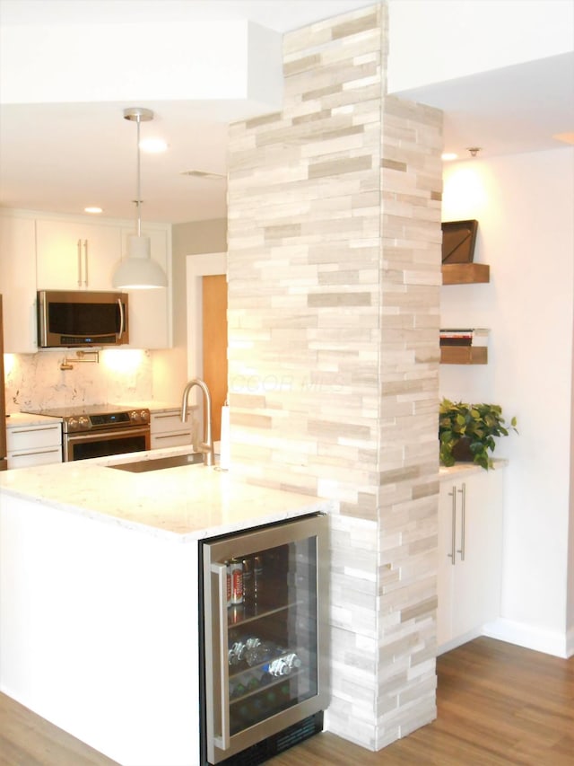 kitchen with appliances with stainless steel finishes, sink, decorative light fixtures, white cabinets, and wine cooler