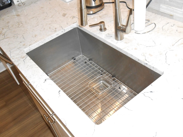 room details featuring dark hardwood / wood-style floors, light stone countertops, and sink