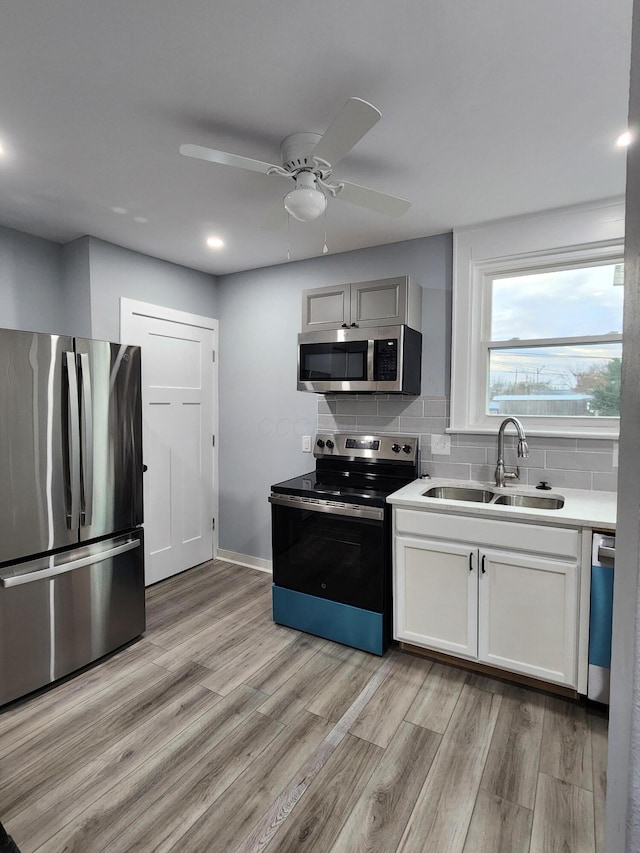 kitchen featuring light wood-style flooring, a sink, light countertops, appliances with stainless steel finishes, and tasteful backsplash