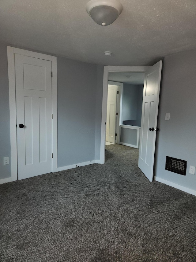 empty room with baseboards, dark carpet, and a textured ceiling