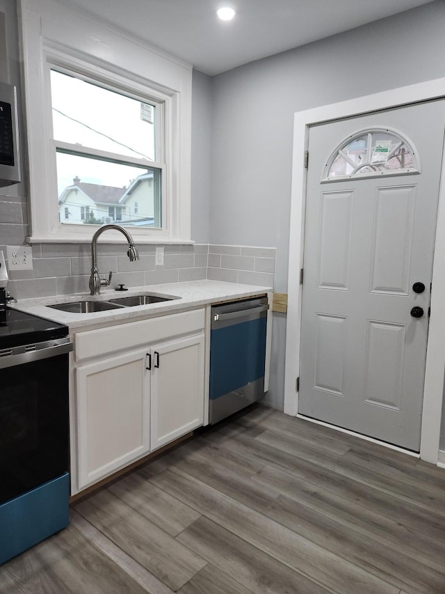 kitchen with a sink, electric range oven, light wood-style floors, dishwasher, and tasteful backsplash