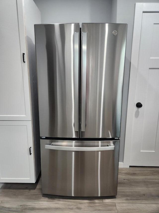 room details with white cabinetry, wood finished floors, and freestanding refrigerator