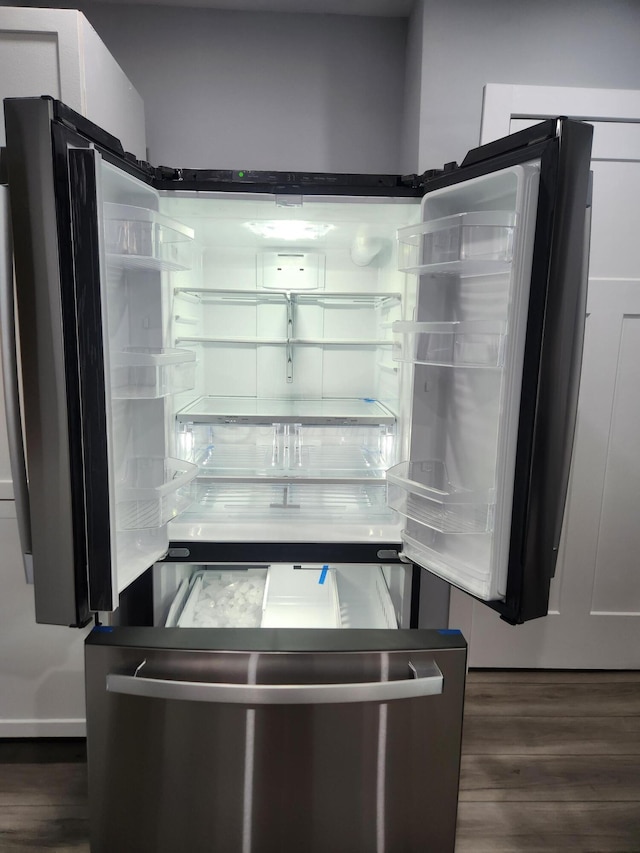 room details with white cabinetry, freestanding refrigerator, and wood finished floors